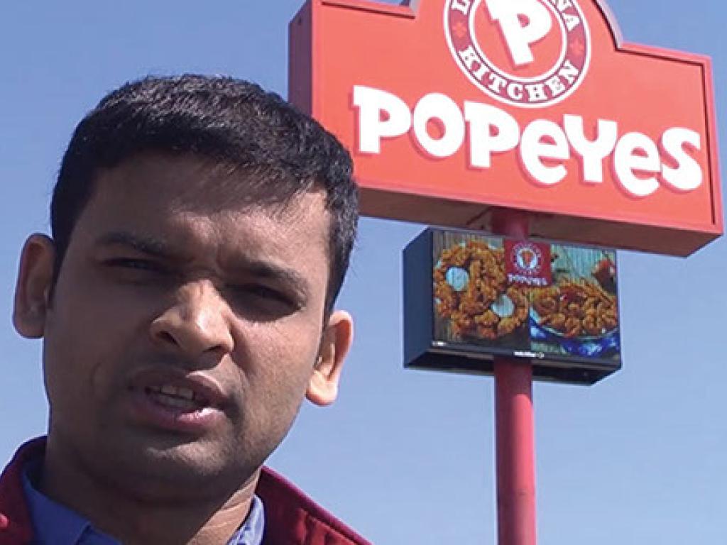 Popeyes sign with LED screen with business owner in frame